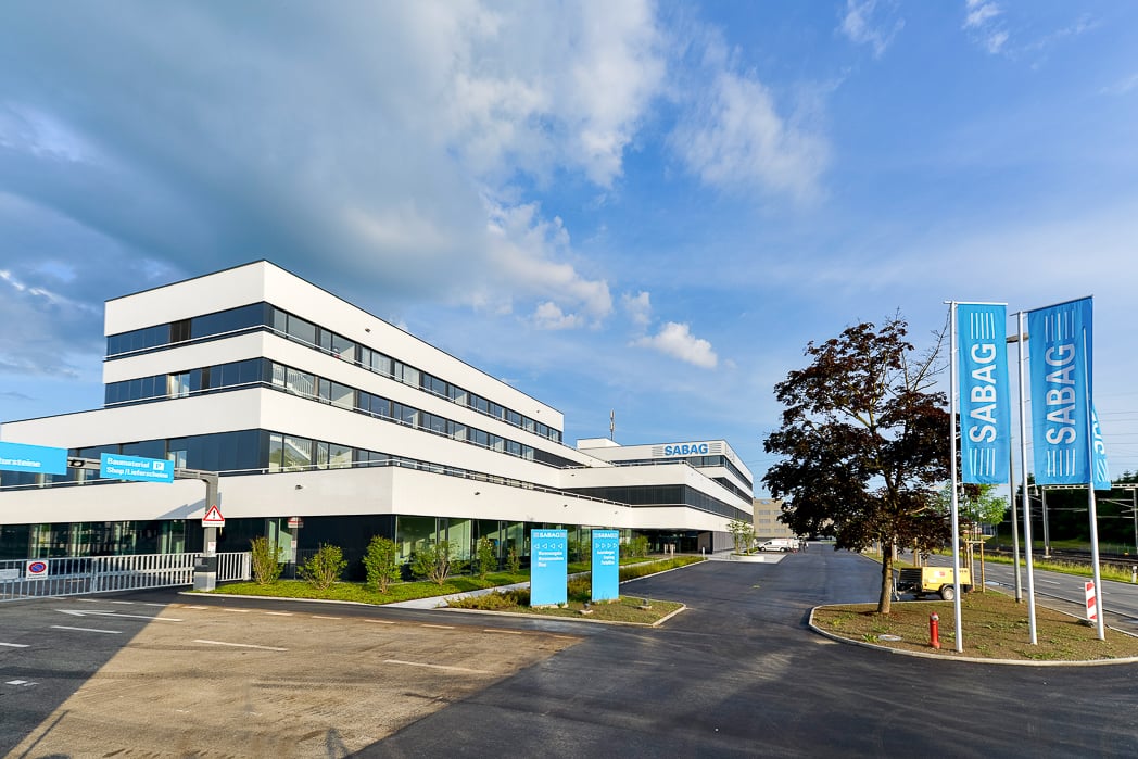 Hauptsitz Gebäude der SABAG AG in Rothenburg von aussen, mit Einfahrt und blauen Fahnen.