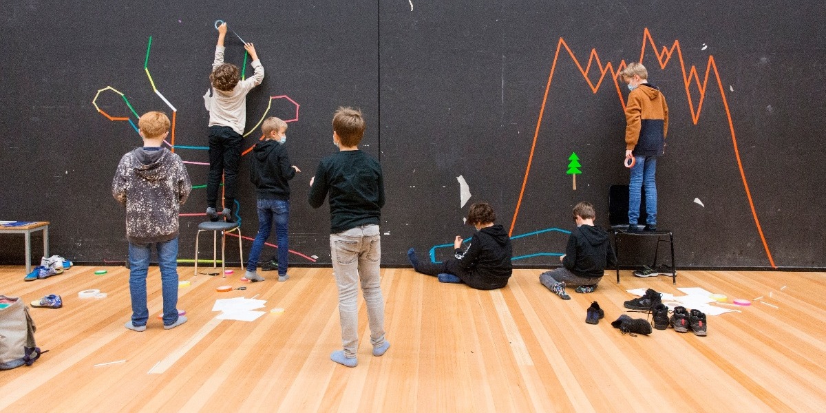 Kinder Gruppe verziert gemeinsam eine schwarze Wand.